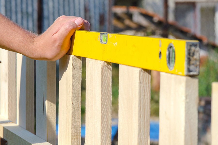 person leveling wooden fence posts